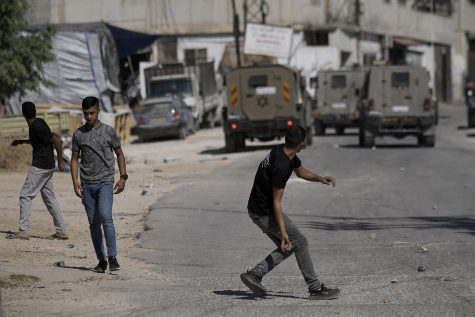 FILE - Palestinians throw stones at an Israeli military vehicle following a military raid of the Askar refugee camp, July 24, 2023, in the West Bank city of Nablus. In negotiations with Israel to free hostages in Hamas captivity in Gaza, the militant group has pushed for the release of high-profile prisoners. But most Palestinians passing through Israel’s ever-revolving prison door are young men arrested in the middle of the night for throwing stones and firebombs in villages near Israeli settlements. (AP Photo/Majdi Mohammed, File)