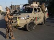 Afghan security forces keep watch at the side of a bomb blast in Kabul