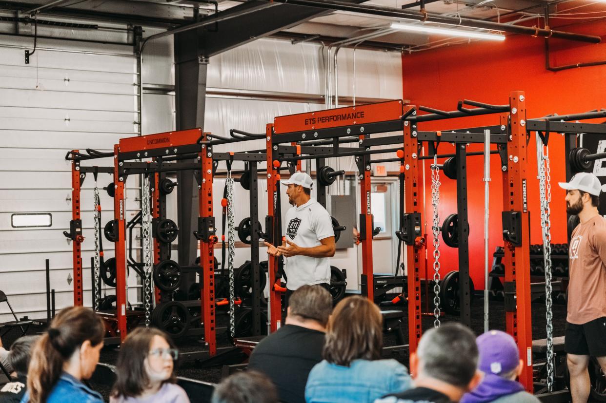 Chad Greenway, standing at center, speaks to people on June 11, 2023, at the opening of Ankeny's ETS Performance training facility for young athletes. He also opened a location in Grimes.