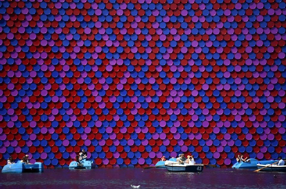 <p>People use boats and pedalos as they pass an artwork, entitled ‘The Mastaba’, by Bulgarian artist Christo Vladimirov Javacheff, better known as ‘Christo’, on the Serpentine lake in Hyde Park in west London on Aug. 6, 2018. (Photo: Ben Stansall/AFP/Getty Images) </p>