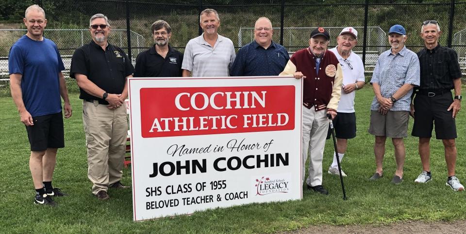 John Cochin, seen here standing next to the sign at right, is surrounded by some of his former players from his days as coach of Sanford High School's baseball team. On July 14, 2023, they and others gathered for Sanford Schools Legacy Foundation's dedication of an SHS baseball field to Cochin.