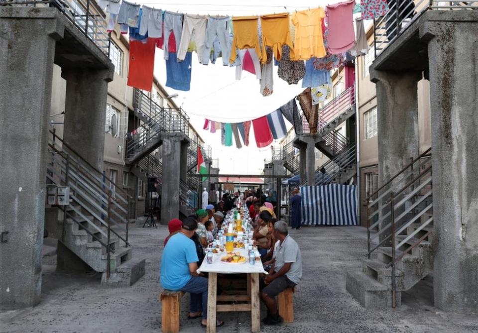 People sit at a long makeshift table in Heideveld on 30 March.