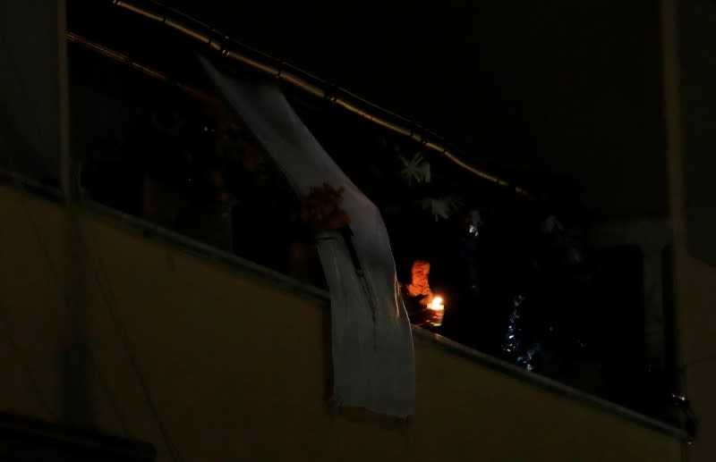 A woman lights a candle on her balcony as faithful across Italy say a prayer for people suffering from coronavirus disease (COVID-19)