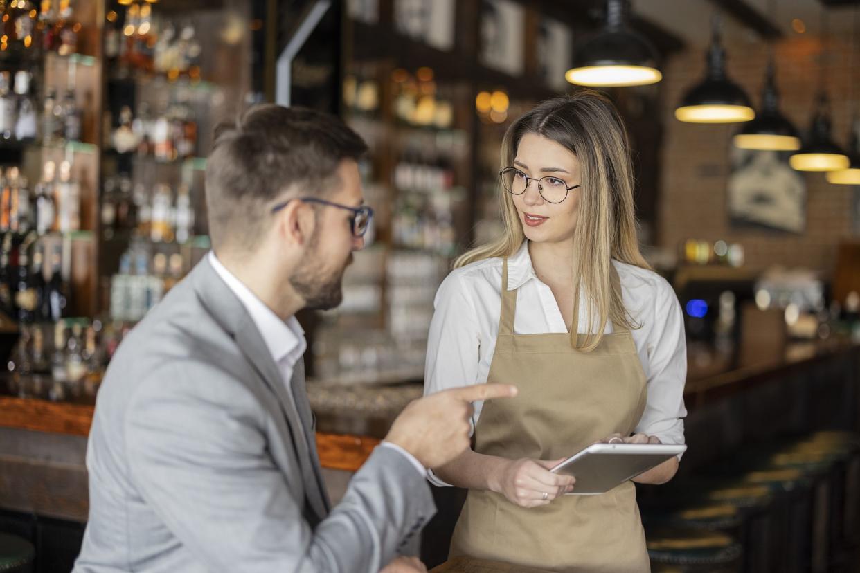 Female waiter taking a customer's order using a tablet computer in a coffee shop