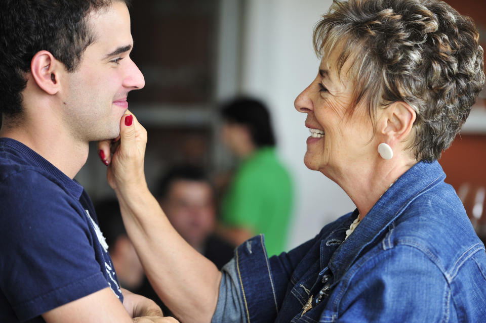 A grandma is pinching her adult grandson's chin