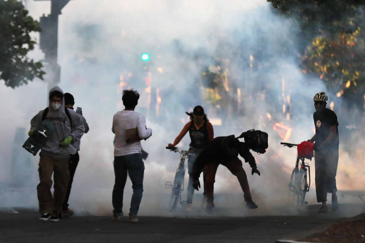 Some protesters move away as police shoot tear gas and flash grenades to disperse the crowd on Broadway near the Oakland Police Department during the fourth day of protests over George Floyd's death by the Minneapolis police in Oakland, CA (Ray Chavez/Digital First Media/East Bay Times via Getty Images)