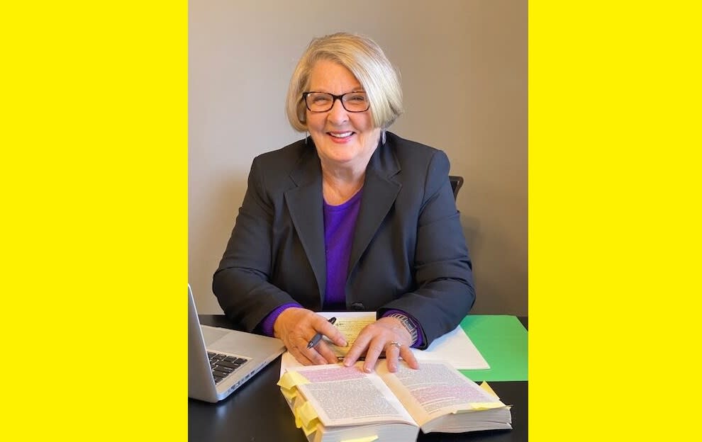 A woman at a desk with a thick book.