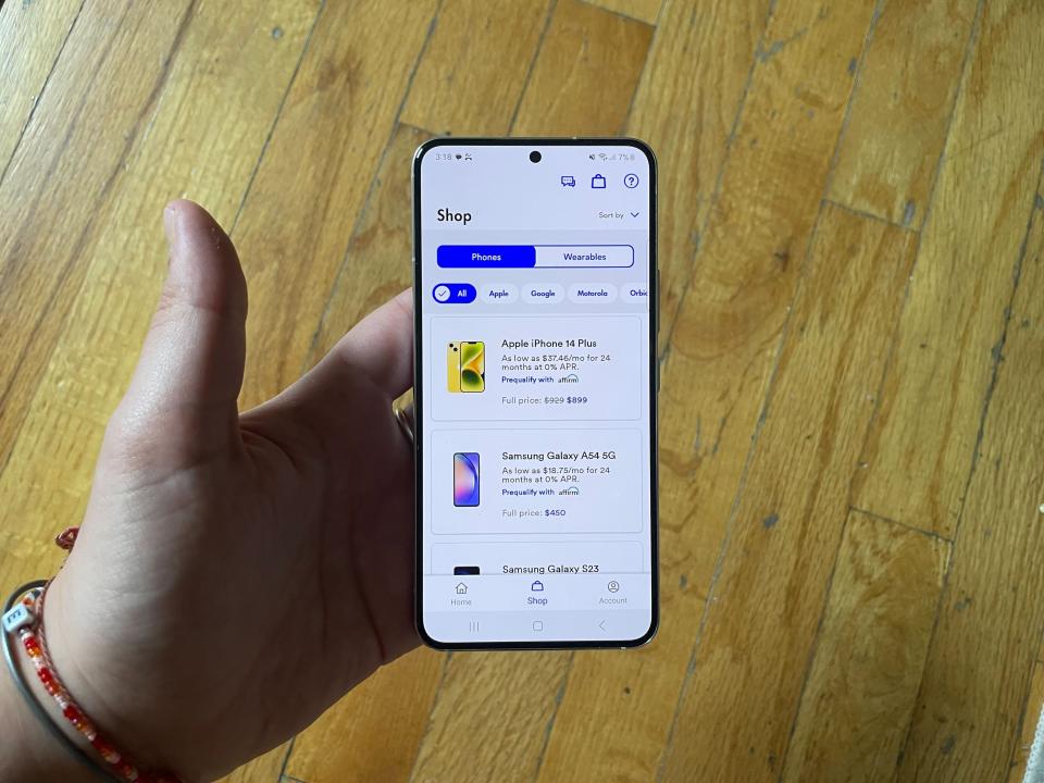 Picture of a phone in hand with the Visible app open to the Shop tab.