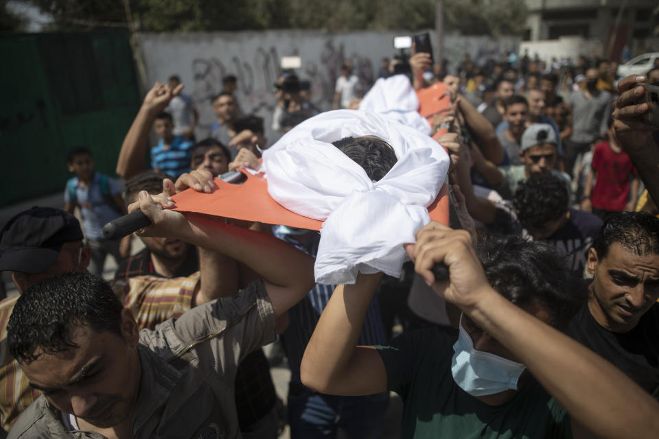 Mourners carry the body of Palestinian Omar al-Nile, 12, who was shot on Saturday during a violent demonstration on the eastern border between Gaza and Israel, during his funeral in Gaza City, Saturday, Aug. 28, 2021. (AP Photo/Khalil Hamra)