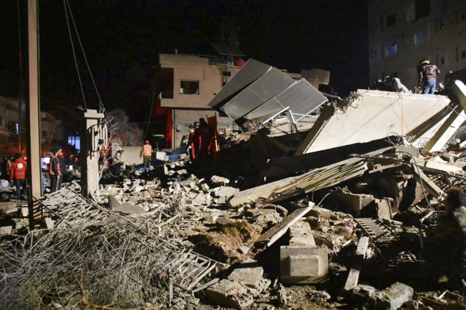 In this photo released by the Syrian official news agency SANA, Syrian security forces and civil defence workers gather next of a building that was destroyed by Israeli airstrikes, in Homs, Syria, late Tuesday, Feb. 6, 2024. Syria's military says Israeli airstrikes over the central city of Homs and nearby areas have killed and wounded civilians. (SANA via AP)