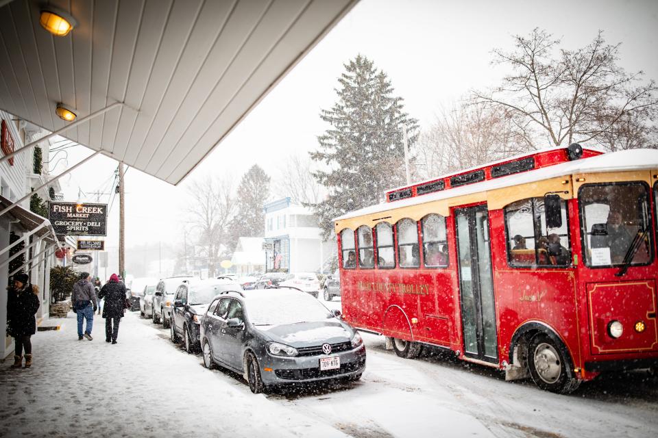 A Door County Trolley travels down the snowy streets of Fish Creek. The company offers a Winter Wine Tour & Sleigh Ride that includes rides in the trolley and a horse-drawn sleigh.