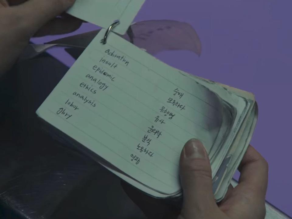 a notecard held on a ring of other notecards. it has words in english written on the left, and their korean counterparts on the right