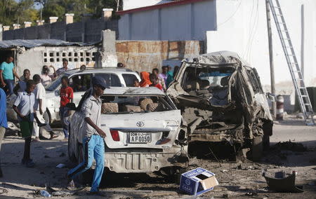 People walk near the wreckage of cars destroyed in a car bomb attack outside beachside restaurant Beach View Cafe on Lido beach, in Somalia's capital Mogadishu, January 22, 2016. REUTERS/Feisal Omar