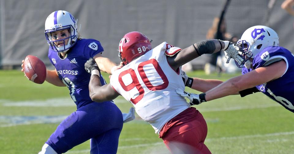 Holy Cross quarterback Marco Siderman looks to escape from pressure by Harvard’s Truman Jones, as Crusader lineman Pat McMurtrie tries to help out