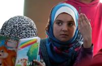 A student gestures as she attends a class inside a bus in the city of al-Bab