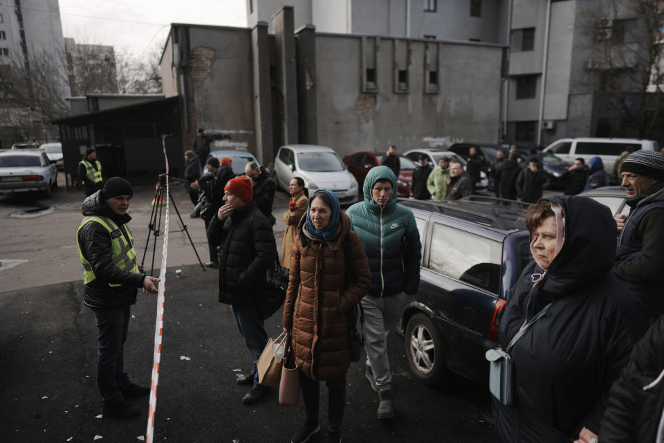 People wait behind police cordon after a rocket attack in Kyiv, Ukraine, Thursday, March 9, 2023. Russia unleashed a massive missile barrage targeting across Ukraine early Thursday, hitting residential buildings and killing an unconfirmed number of people in the largest such attack in three weeks. (AP Photo/Thibault Camus)