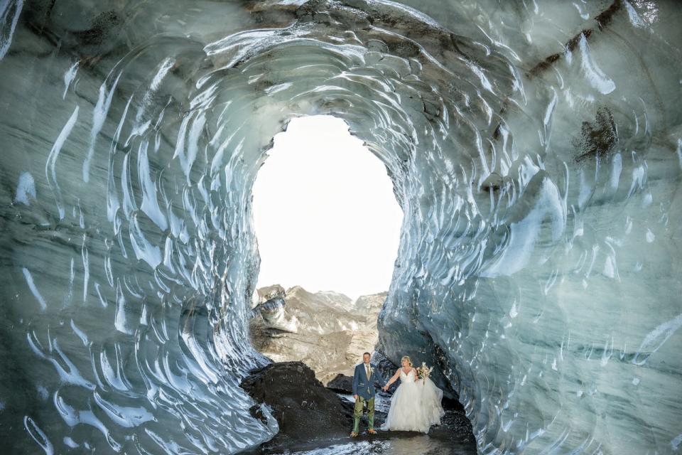 A bride and groom pose for photos in an ice cave