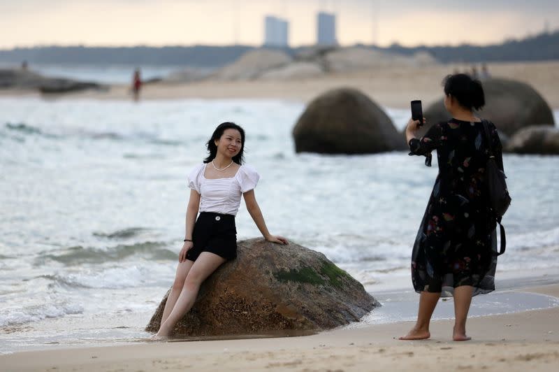 A woman poses for pictures on a beach in front of the Wenchang Space Launch Center, in Wenchang, Hainan