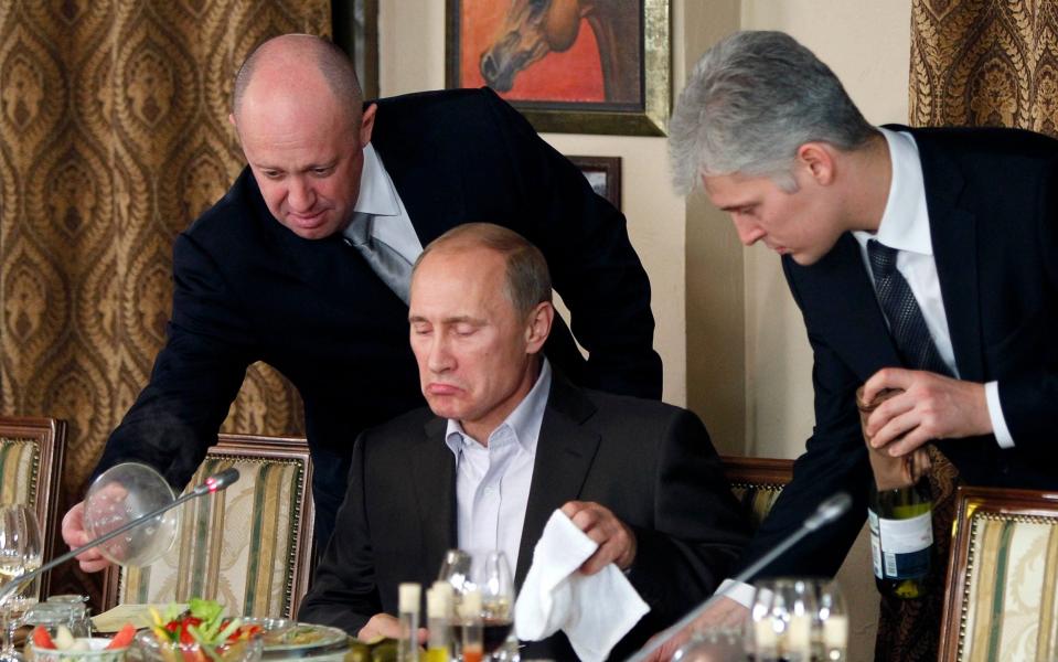 Yevgeny Prigozhin, left, serves food to Vladimir Putin, center, during dinner at Prigozhin's restaurant outside Moscow, Russia. Nov 11, 2011. - Misha Japaridze/AP POOL