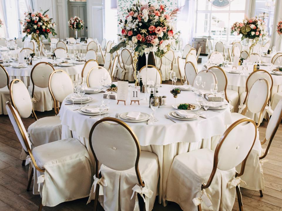 Wedding venue with lots of white chairs around tables with flowers