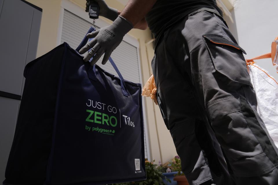 Waste collection crew member uses a portable scale to weight trash for recycling on the Aegean Sea island of Tilos, southeastern Greece, Monday, May 9, 2022. When deciding where to test green tech, Greek policymakers picked the remotest point on the map, tiny Tilos. Providing electricity and basic services, and even access by ferry is all a challenge for this island of just 500 year-round inhabitants. It's latest mission: Dealing with plastic. (AP Photo/Thanassis Stavrakis)