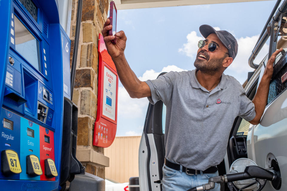 Guy Benhamou sends a picture of gas prices to friends while pumping gas at an Exxon Mobil gas station on June 09, 2022 in Houston, Texas. (Photo by Brandon Bell/Getty Images)