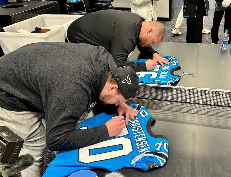 Panthers offensive linemen Brady Christensen (left) and Bradley Bozeman sign jerseys on the ping pong table in the Carolina locker room on clean-out day - Monday, Jan. 8, 2024. The Panthers finished 2-15 with their second straight shutout loss the day before, then cleaned out their lockers Monday in preparation for the offseason.
