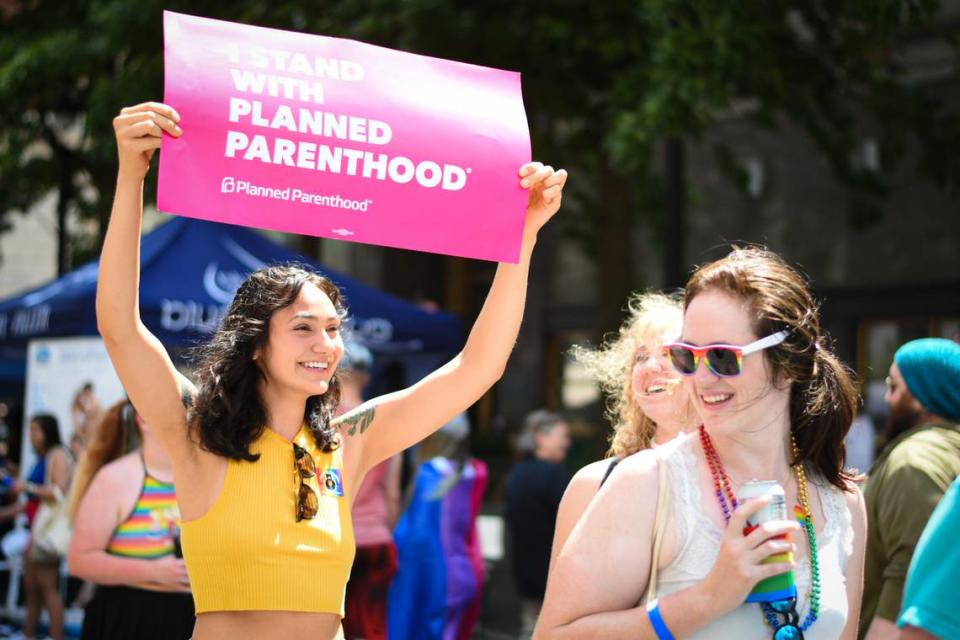 Sydney Lujan (left) is pictured holding an “I Stand For Planned Parenthood” sign while walking along Fayetteville Street at the Out! Raleigh Pride festival in downtown Raleigh on Saturday, June 25, 2022.