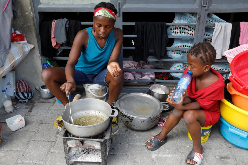 A woman cooks at shelter for families displaced by gang violence, in Port-au-Prince, Haiti, Friday, March 8, 2024. The violence as anti-government gangs battle police in the streets has crippled Haiti’s economy and made it extremely difficult for many of the country's most vulnerable to feed themselves.(AP Photo/Odelyn Joseph)