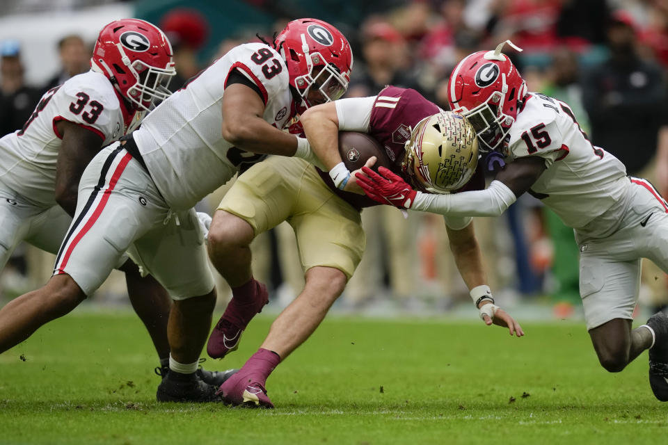 Florida State quarterback Brock Glenn (11) is tackled by Georgia defensive lineman Tyrion Ingram-Dawkins (93) and Georgia defensive back Daniel Harris (15) in the first half of the Orange Bowl NCAA college football game, Saturday, Dec. 30, 2023, in Miami Gardens, Fla. (AP Photo/Rebecca Blackwell)