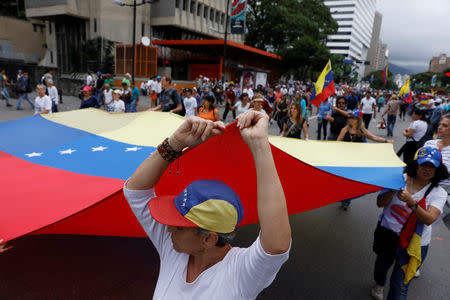 Demonstrators hold a Venezuelan flag while rallying against Venezuela's President Nicolas Maduro in Caracas, Venezuela May 1, 2017. REUTERS/Carlos Garcia Rawlins