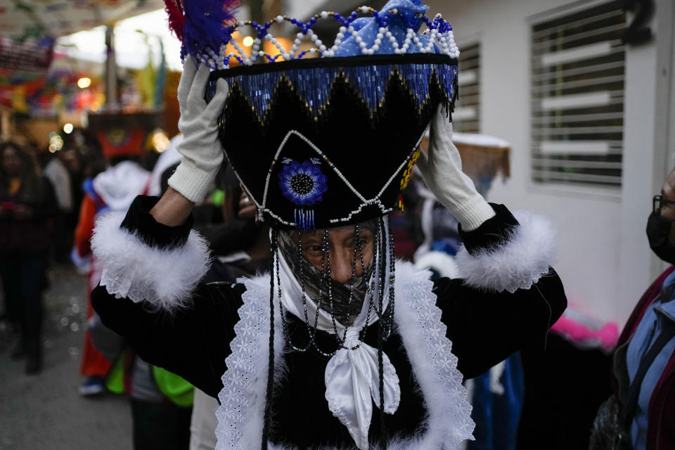 A Mexican "chinelo" dancer adjusts his hat for the procession of "Niñopan" during a Christmas "posada," which means lodging or shelter, in the Xochimilco borough of Mexico City, Wednesday Dec. 21, 2022. For the past 400 years, residents have held posadas between Dec. 16 and 24, when they take statues of baby Jesus in procession to church for Mass to commemorate Mary and Joseph's cold and difficult journey from Nazareth to Bethlehem in search of shelter. (AP Photo/Eduardo Verdugo)