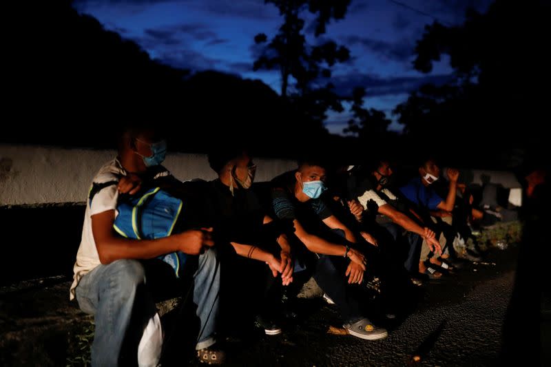 Honduran migrants trying to reach the U.S. rest on a curb as Guatemalan soldiers block a road to stop migrants from reach the Mexico's border, in San Pedro Cadenas