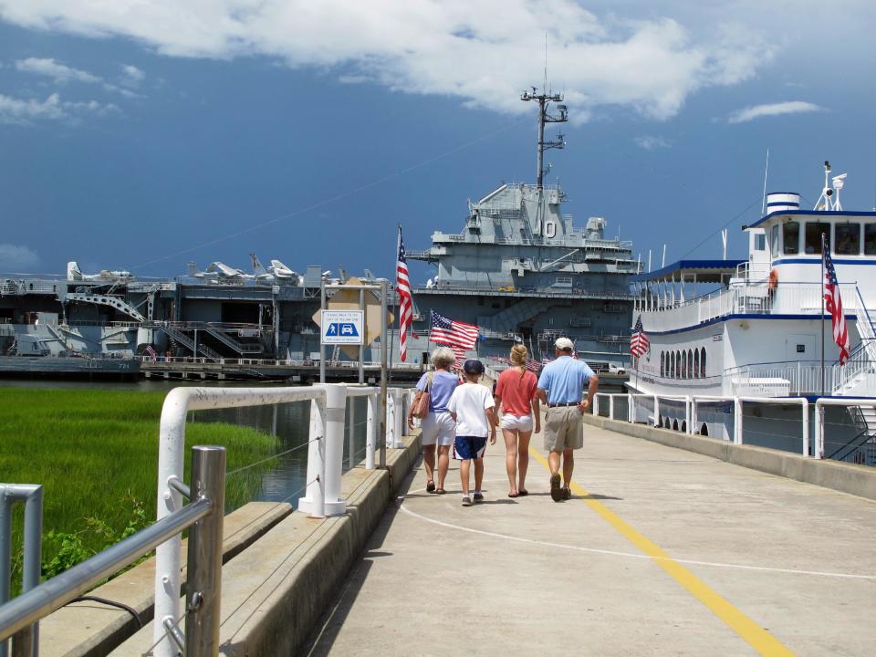 FILE - In this Aug. 7, 2012 file photo, visitors walk toward the USS Yorktown at the Patriots Point Naval and Maritime Museum in Mount Pleasant, S.C. Tourism is an $18 billion industry in South Carolina and a new season is gearing up the week of February 9, 2014 with the Governor's Conference on Tourism and Travel on Hilton Head Island, the Southeastern Wildlife Exposition in Charleston and other events. (AP Photo/Bruce Smith, File)