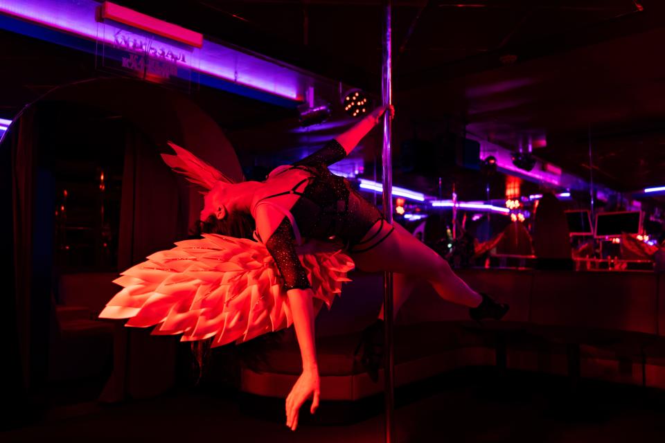 Woman wearing angel wings dancing on strip club.