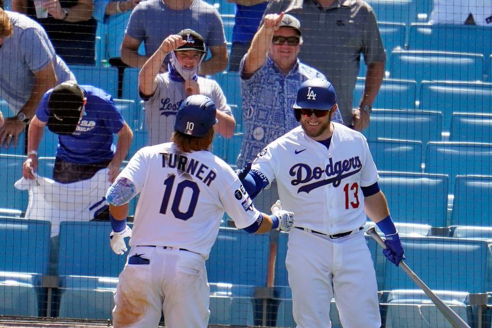 Los Angeles Dodgers' Justin Turner (10) is congratulated by Max Muncy (13) after hitting a solo home run in the sixth inning of a baseball game against the Washington Nationals, Friday, April 9, 2021, in Los Angeles. (AP Photo/Marcio Jose Sanchez)