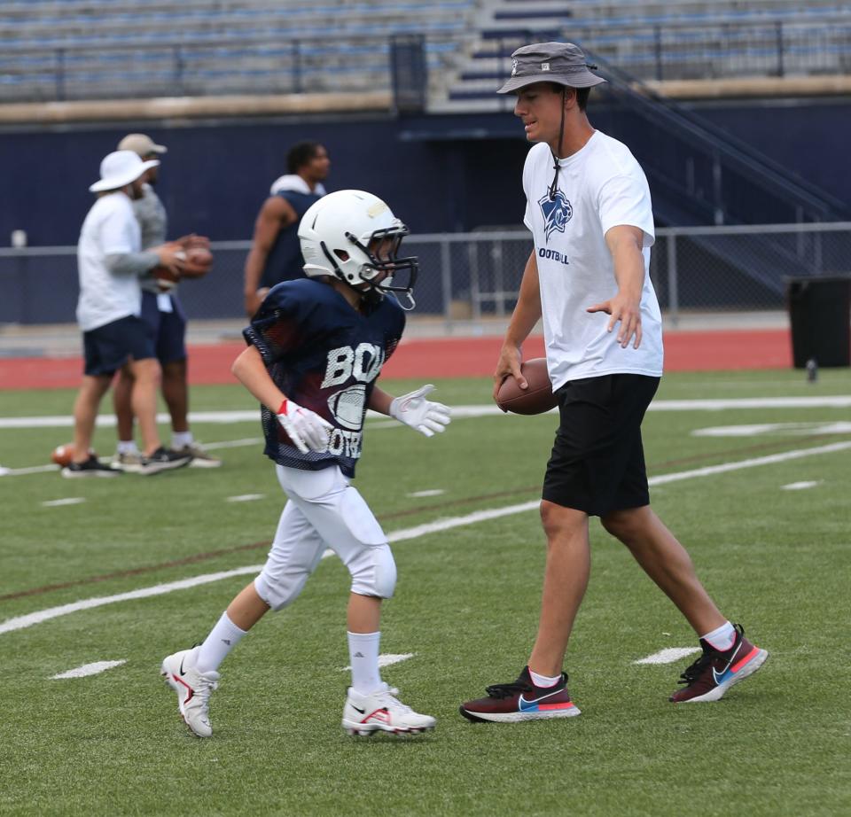 A UNH football player gives a high-five to a youngster at the program's annual youth football camp this week.