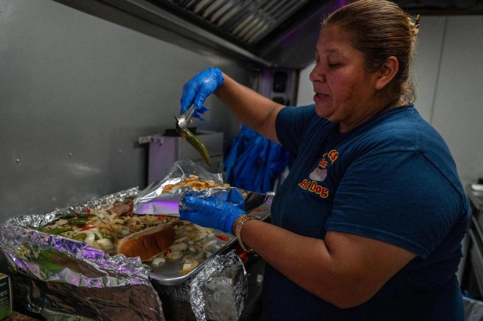 Inside her food truck, La Casa Del Hot Dog, Lisseth Juarez prepares a California-style hot dog, which comes wrapped in bacon and topped with onions and peppers.
