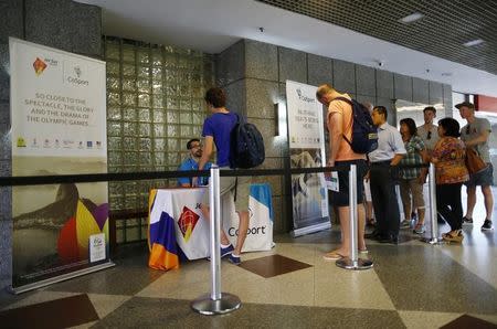 Clients of CoSport, a firm that holds a U.S. Olympic Committee-granted monopoly to sell Rio 2016 events tickets, wait at a booth for information on where to pick up the tickets they purchased online, in Rio de Janeiro August 1, 2016. REUTERS/Ivan Alvarado