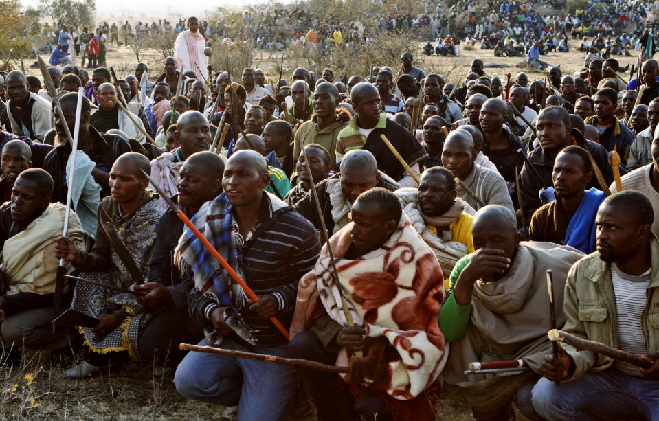 Striking miners chant slogans as they hold crudely made weapons and machetes at the Lonmin mine near Rustenburg, South Africa, Wednesday, Aug. 15, 2012. The unrest at the Lonmin mine began Friday, as some 3,000 workers walked off the job over pay in what management described as an illegal strike. (AP Photo/Denis Farrell)