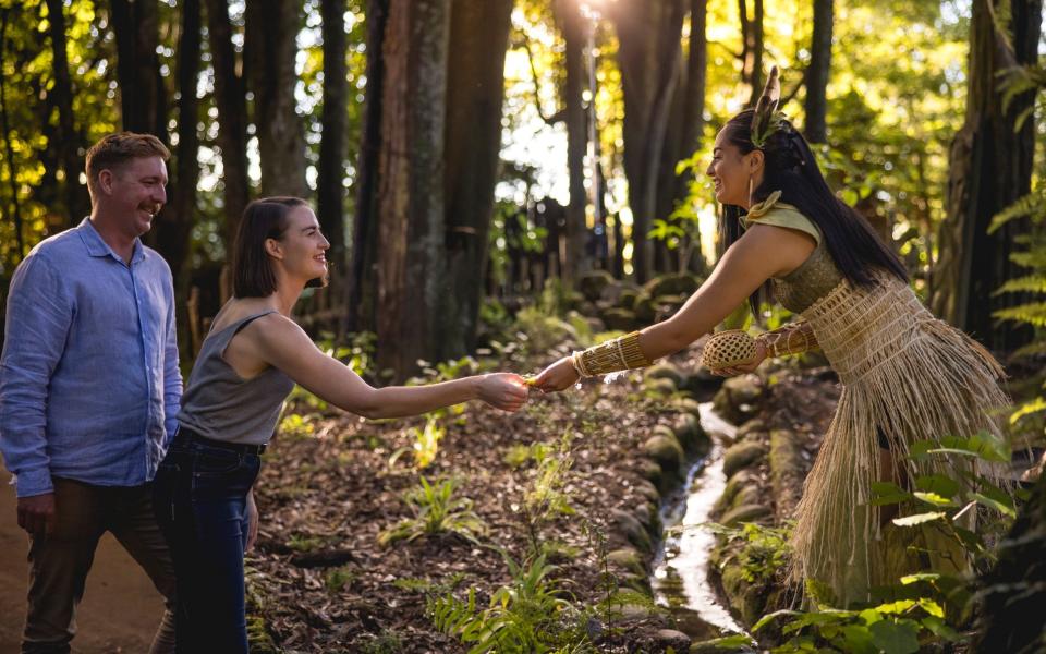 A woman shakes hands with a woman in traditional Māori clothing