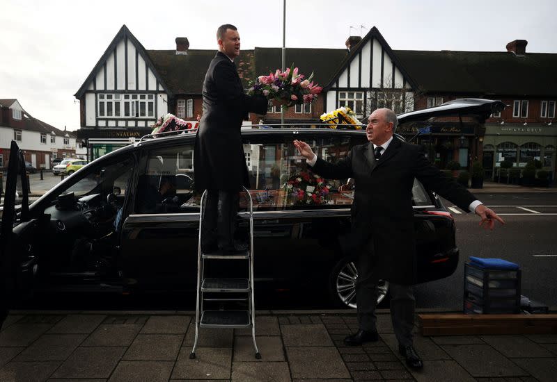 Funeral conductor Spencer Baxter and pallbearer Doug Austin from W. Uden & Sons Family Funeral Directors prepare a hearse ahead of a funeral in Bromley, amid the coronavirus disease (COVID-19) pandemic, in south east London