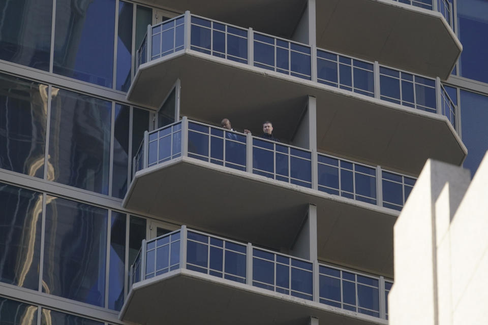 Authorities gather on a balcony in a residential builing, Wednesday, Oct. 20, 2021, in Atlanta. Police in Atlanta have closed streets around at least four square blocks of office and apartment buildings in response to gunfire in the city's midtown area. (AP Photo/Brynn Anderson)