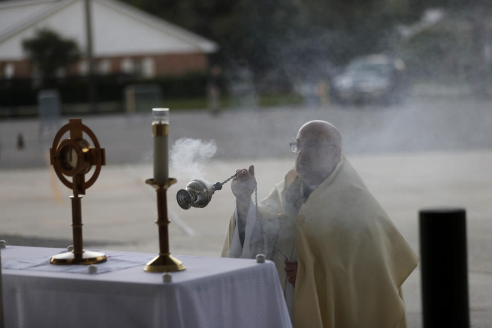 Fr. Steve Buno, Pastor of St. Rita of Cascia Catholic Church in Harahan, La., burns incense as he waits for more cars, ash performs drive-thru Benediction of the Blessed Sacrament, as a form of social distancing due to the new coronavirus, during Holy Week, Tuesday, April 7, 2020. (AP Photo/Gerald Herbert)