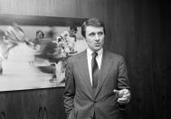 FILE - In this Wednesday, Feb. 6, 1980 file photo, Herb Brooks, coach of the 1980 U.S. Olympic Hockey team, stands in front of a hockey photo at the Hall of Fame Club at Madison Square Garden in New York. The NCAA men's hockey tournament bracket this year would have made Herb Brooks proud. For the first time, all five Division I programs from Minnesota made the 16-team field. Minnesota is the No. 3 overall seed. The Gophers are joined by Minnesota State, Minnesota Duluth, St. Cloud State and Bemidji State. Brooks was a player and coach for Minnesota who went on to Olympic and NHL fame. He also helped launch St. Cloud State's leap to Division I in 1987. Brooks spoke often of his desire to grow the college game in his home state. (AP Photo/Ron Frehm, File)