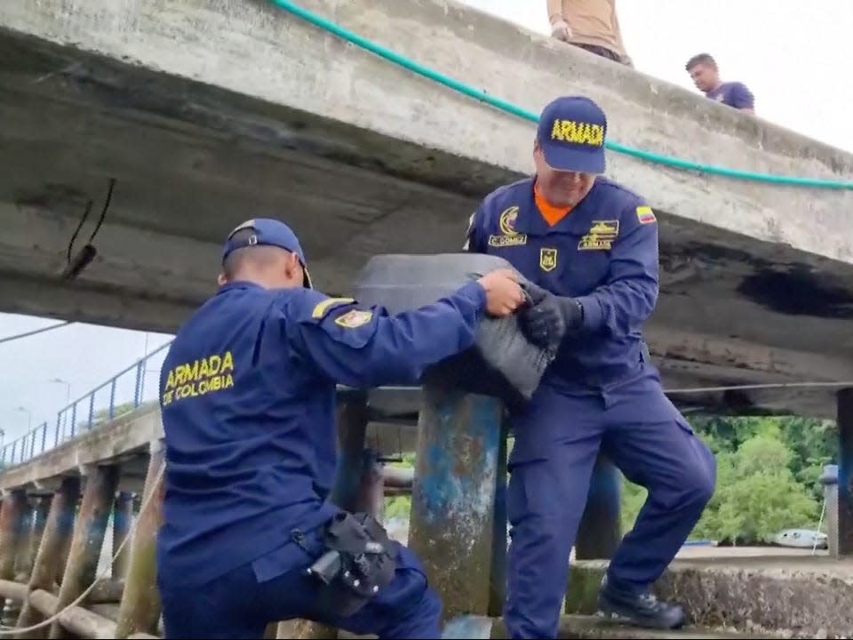 Colombian navy officers carry the bundles of cocaine that were seized from the submarine.