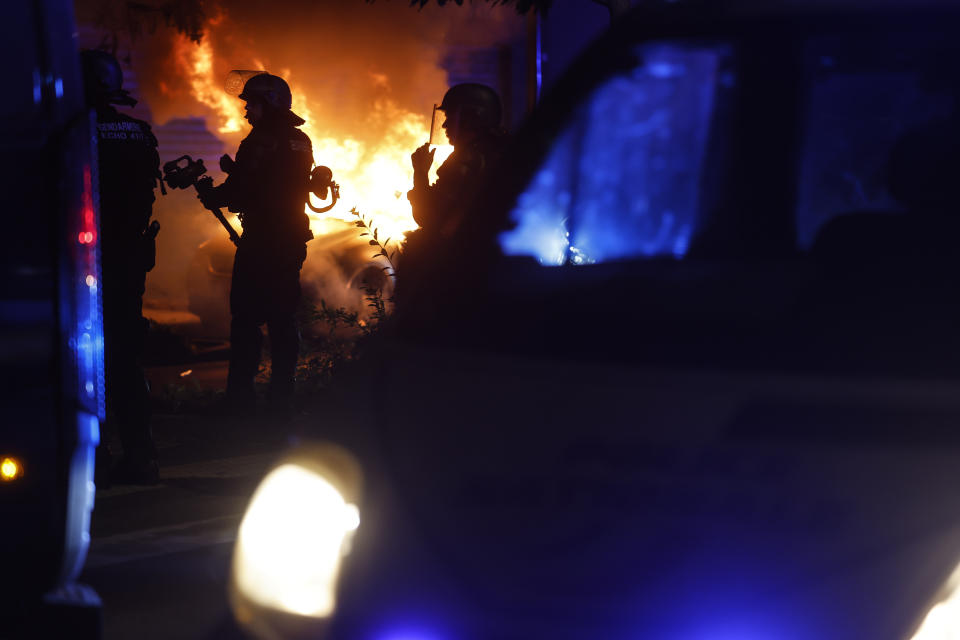 FILE - Riot police stand near a burning car in the La Meinau neighborhood of Strasbourg, eastern France, Friday, June 30, 2023. Small-town mayors where vehicles were torched, fires lit and police attacked are scratching their heads, trying to figure out why them, why now and whether France's urban blights that previously seemed far away are sinking roots into their peace and quiet, too. (AP Photo/Jean-Francois Badias, File)