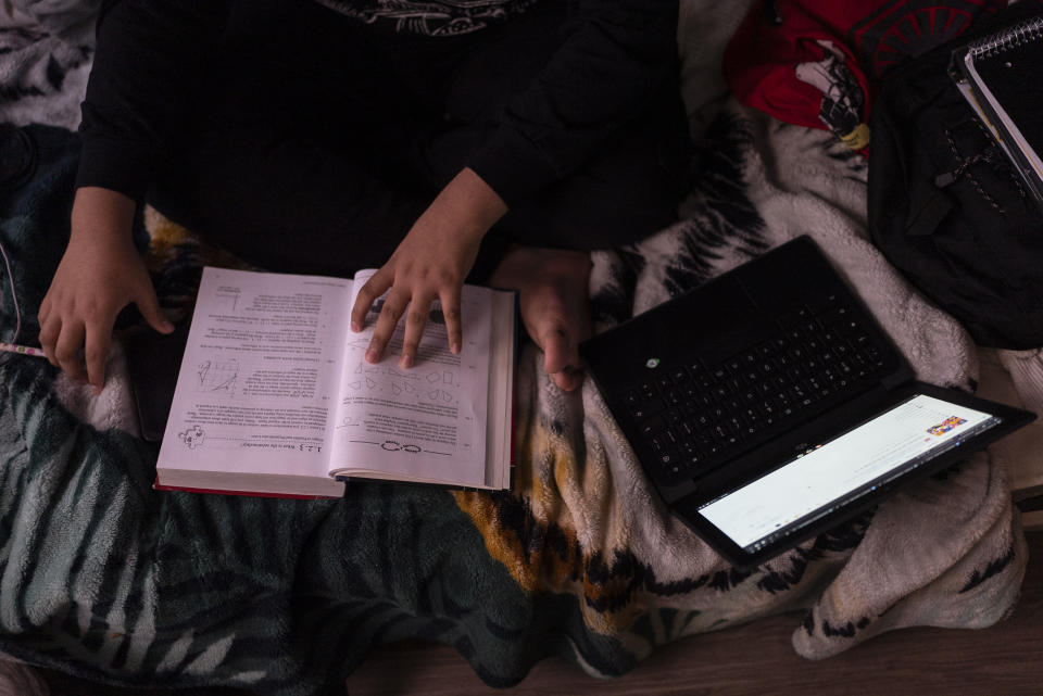 Deneffy Sánchez, de 15 años, hace su tarea en la laptop de la escuela en una litera que comparte con su madre y hermanita en un apartamento tipo estudio, donde su familia paga 700 dólares al mes a un compañero de piso para rentar el espacio, el sábado 9 de septiembre de 2023, en Los Ángeles. (AP Foto/Jae C. Hong)