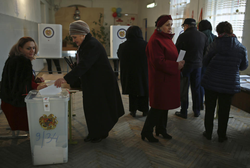 A woman casts her ballot paper in a polling station during an early parliamentary election in Yerevan, Armenia, Sunday, Dec. 9, 2018. The charismatic 43-year-old Nikol Pashinian took office in May after spearheading massive protests against his predecessor's power grab that forced the politician to step down. (Vahan Stepanyan/PAN Photo via AP)