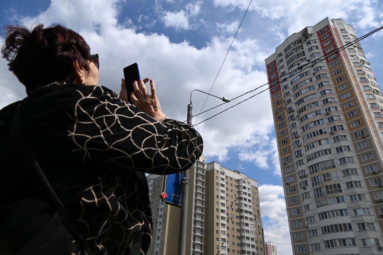 A woman takes a picture of a damaged multi-story apartment building after a reported drone attack in Moscow in May 2023.